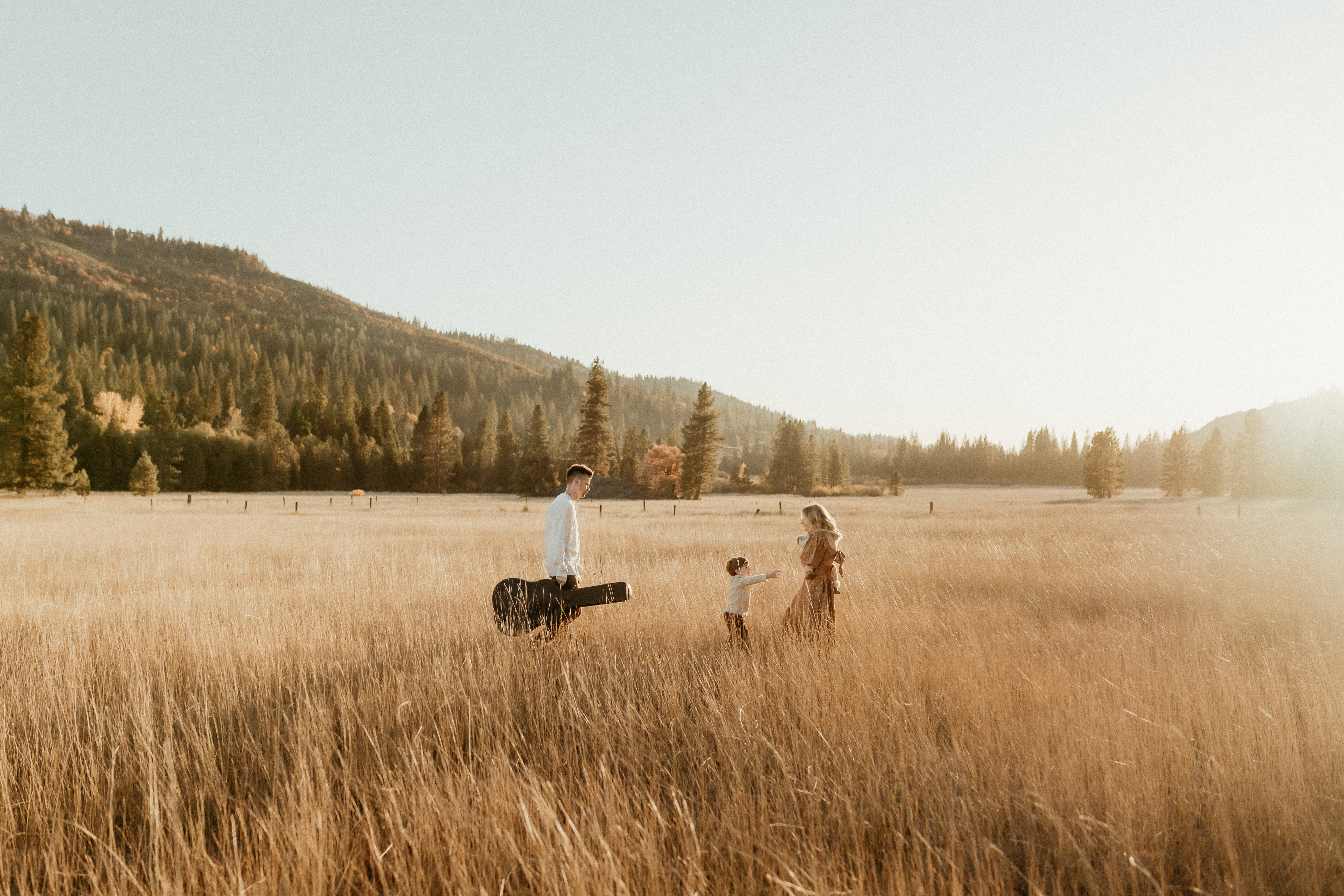 family of four at sundet in a golden field with guitar